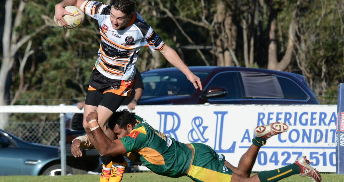 Wingham winger Michael Bailey is grassed by veteran Forster-Tuncurry utility player Chris Simon during the Group Three Rugby League game played at Wingham.