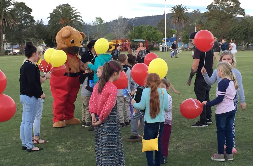 children getting balloons from LJ Hooker Bear at the Cinema Under the Stars 2016 event in Central Park Wingham.