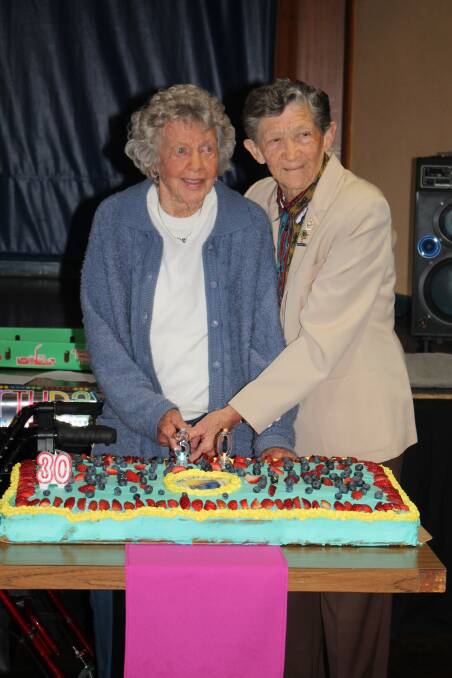 Netta Summerville and Marie Hatchwell had the honour of cutting the birthday cake. Photo: Pam Muxlow