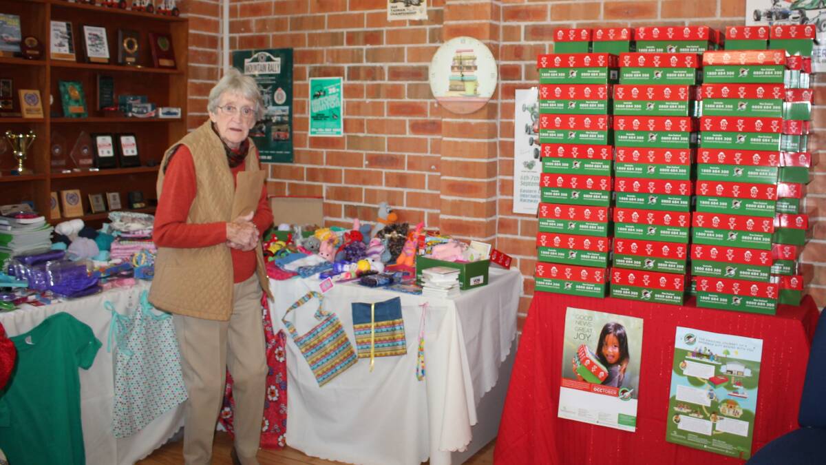 Joan Forrester standing beside the table of goodies that will go into the 80 Operation Christmas Child boxes.