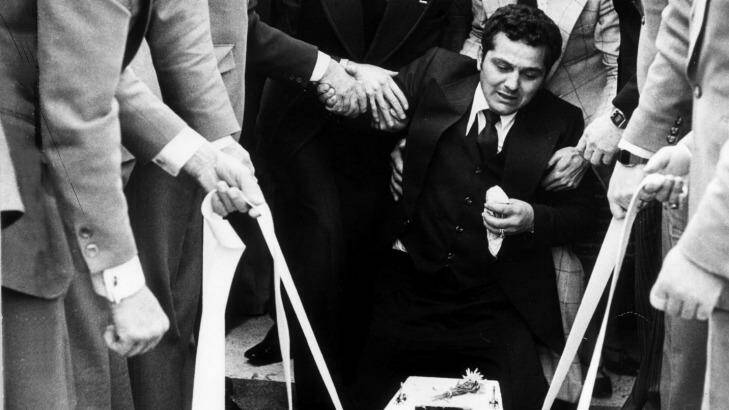 Essendon 1978: Sam Gulle is supported by friends as the body of his 4-week-old son is lowered into the grave. Photo: Bruce Postle