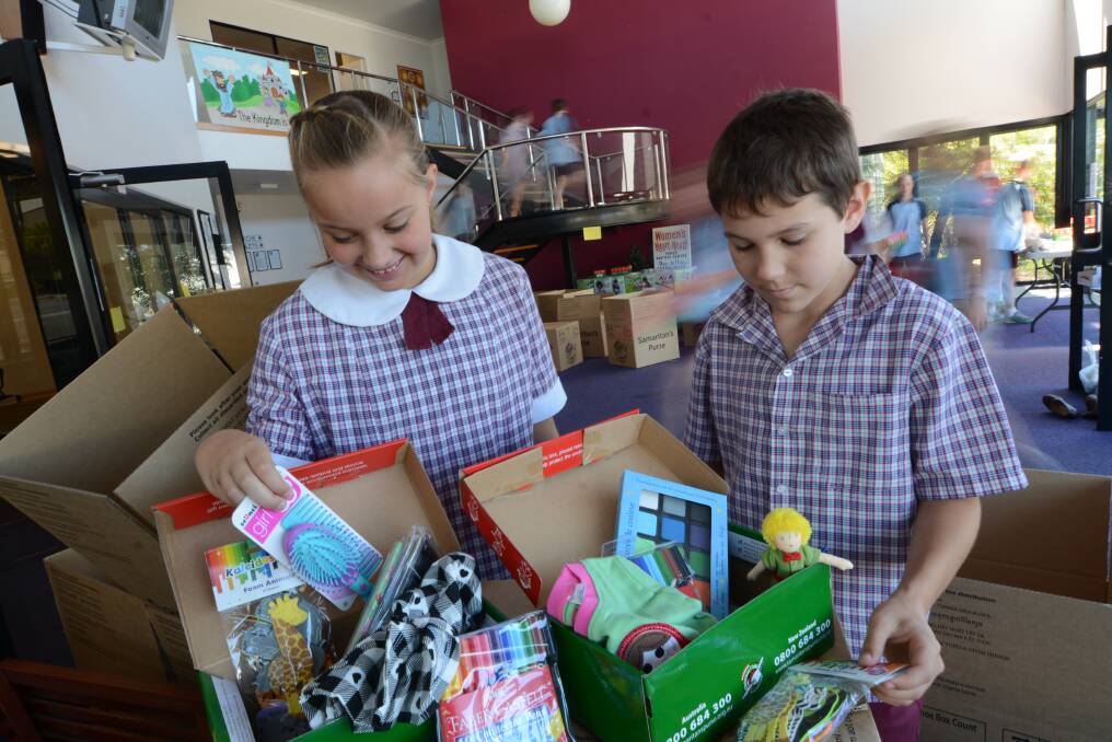 Operation Christmas Child boxes are filled with fabulous gifts. Taree Christian College students Amarah Budden and Noah Foakes look to the gifts that will be sent to two young girls.