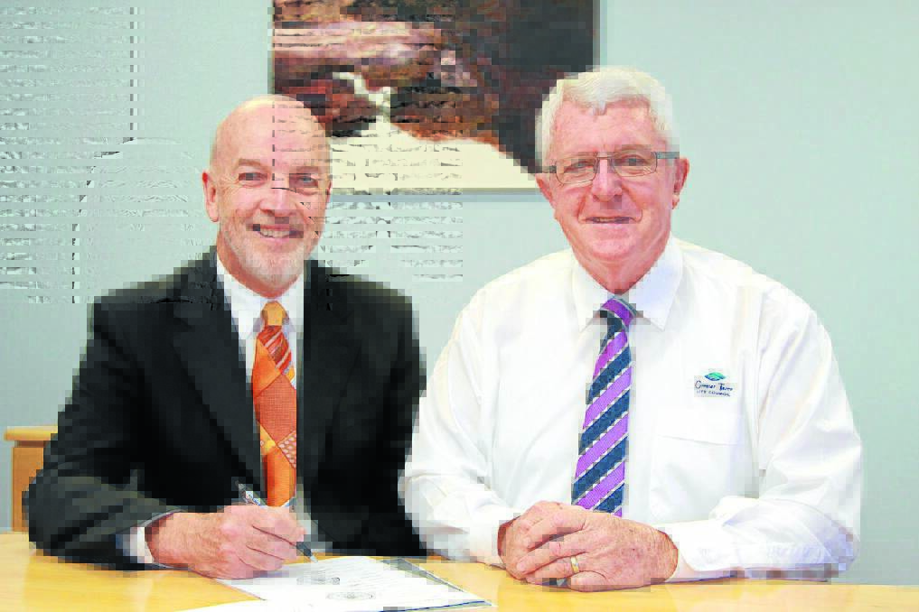 Greater Taree City Council's newly appointed general manager, Ron Posselt signs to paperwork with mayor Paul Hogan.