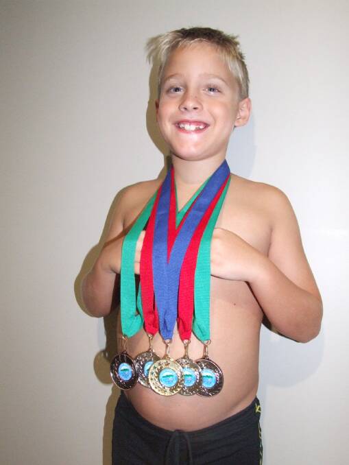 Wingham Swimming Club junior Joshua Wicks with his medal haul from the NSSA swimming carnival in Gloucester