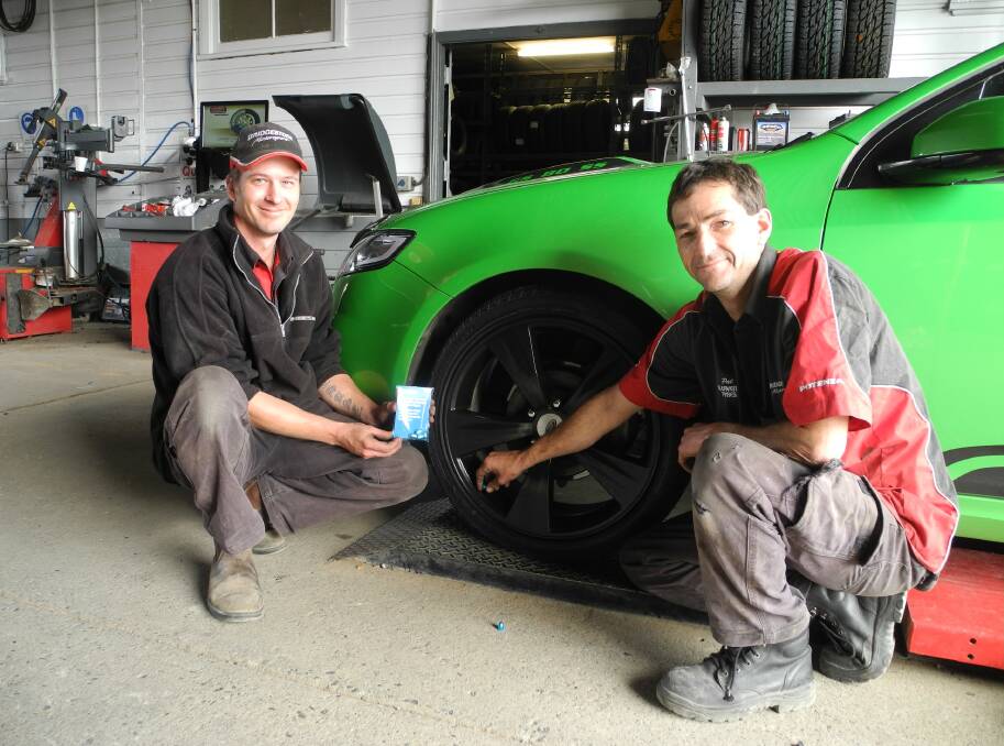 Damien Murray (left) and Patrick Turner at the Bridgestone Service Centre Wingham fit a blue valve cap to a customer's car.