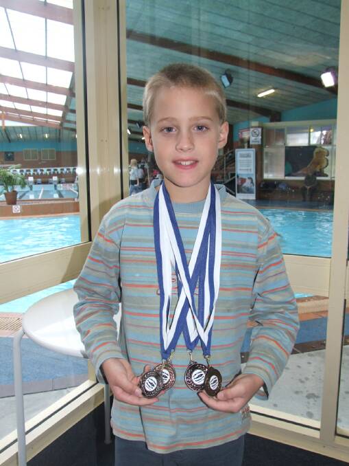 Eight-year-old Josh Wicks of Wingham Swimming Club with his medal haul at the Forster Aquatic Carnival.