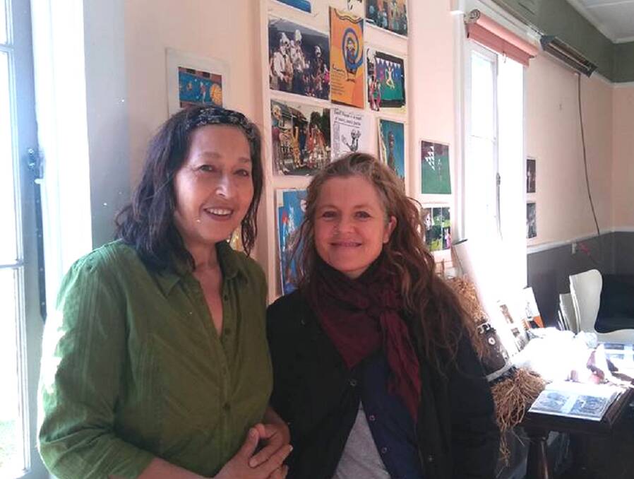 Peggy van Zalm and Jenny Causer in front of photos of Geoffrey Nant's large scale puppets, street theatre characters and community murals