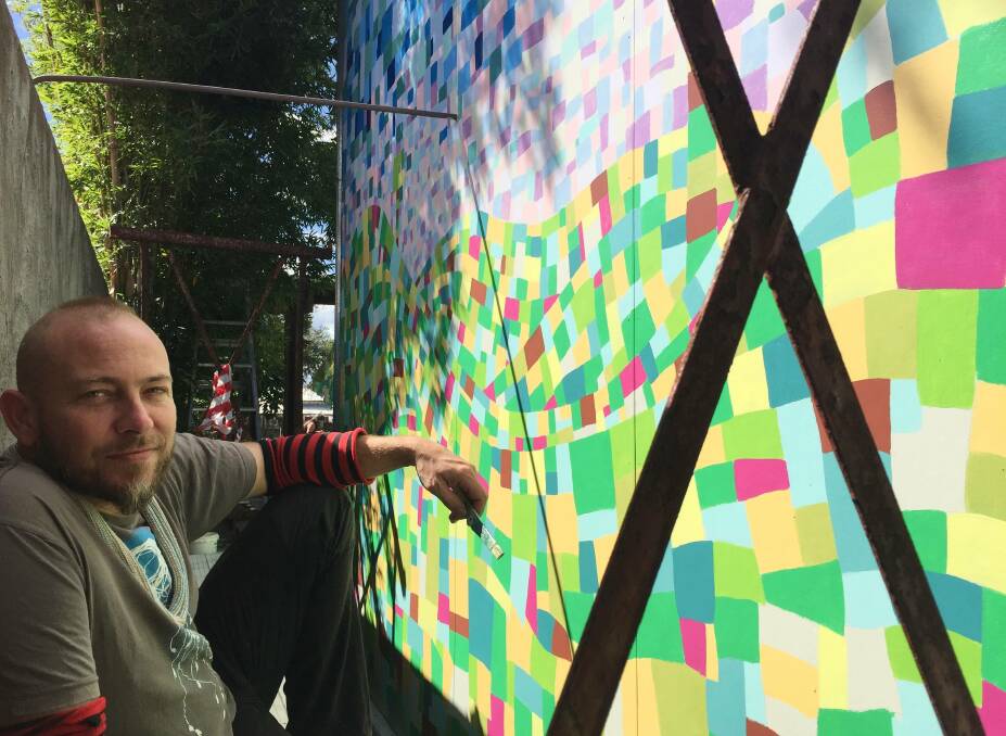 Behind the scaffolds: Artist Mykey Carlier doesn't have a lot of room to move while working on the mural. Photo: Julia Driscoll