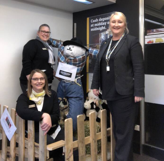 Determined: Commonwealth Bank Wingham branch manager Jaimie Mathiske (front) and staff Ruth Lovell and Rachel Ford Brame, with Patch the scarecrow. Photo: supplied