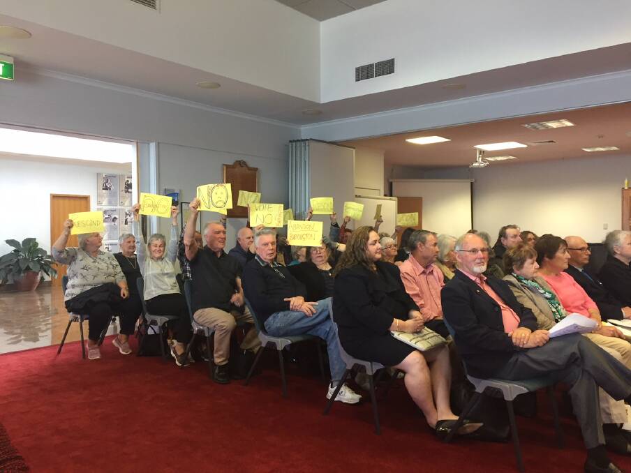 Some members of the gallery at the August 22 ordinary meeting of MidCoast Council held up signs in protest of the 'Barrington Coast' destination name.