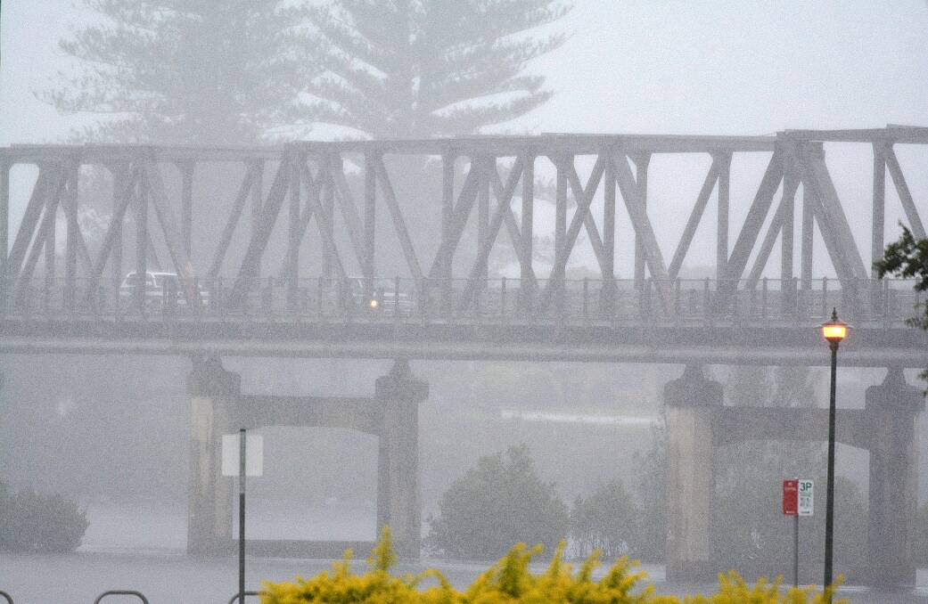 Vehicles drive over the Martin Bridge in heavy rain.